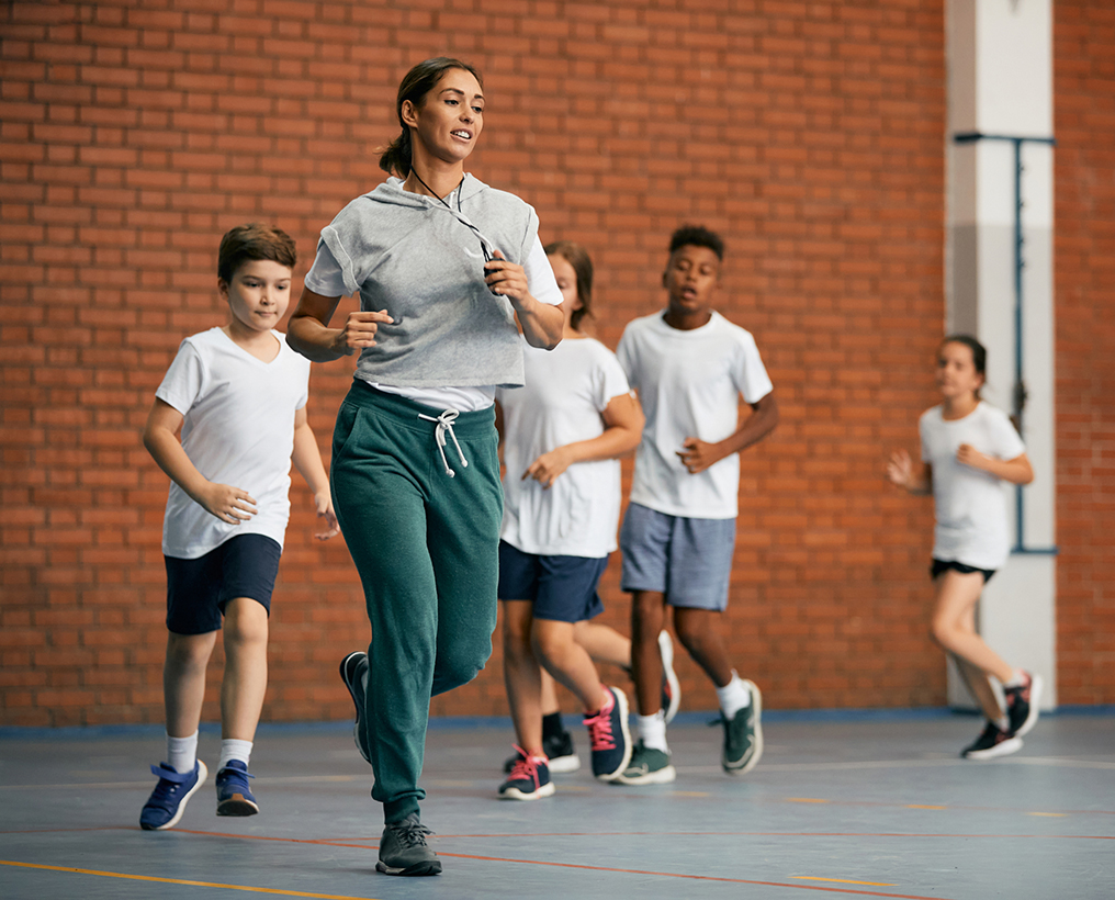 class of kids running besides their physical education teacher